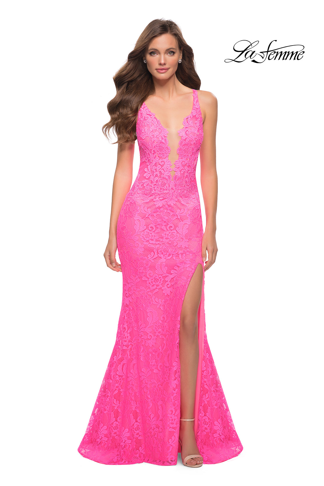 A woman wears the Deep V-Neck Long Lace Prom Dress: La Femme 29978—bright pink with thin straps and a high slit—standing against a white background.
